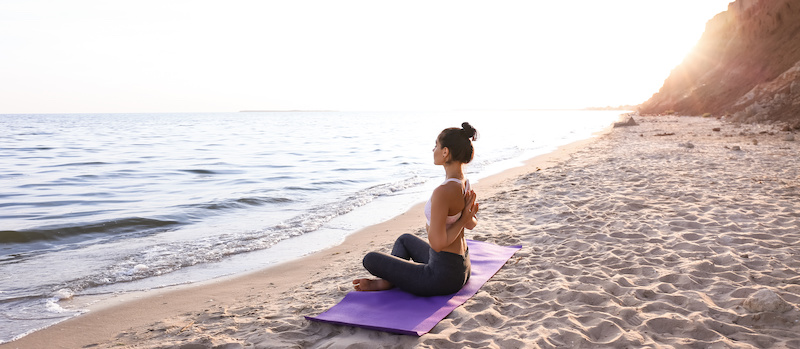 Woman practicing yoga on sea shore