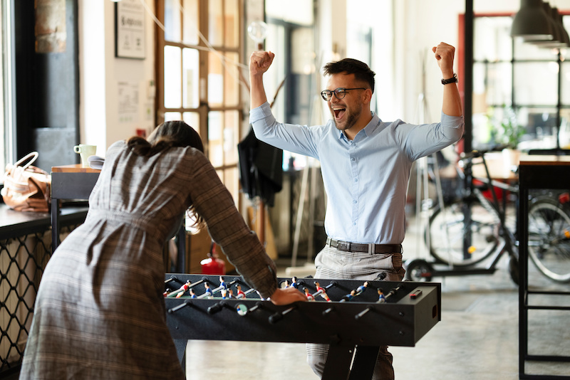 Colleagues having fun at work playing in the work game room